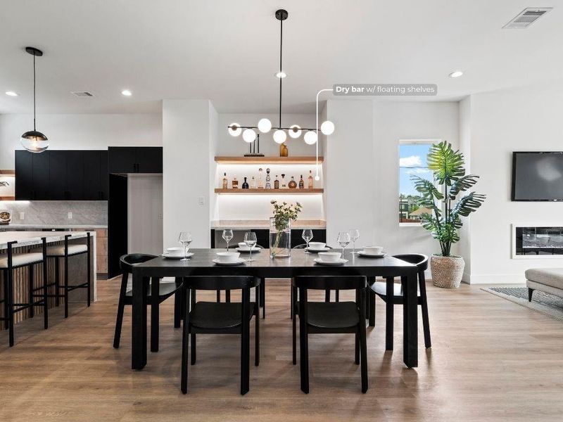 The dining area flows naturally into the kitchen and living room, featuring a built-in dry bar with floating shelves and a beverage cooler, perfect for entertaining.
