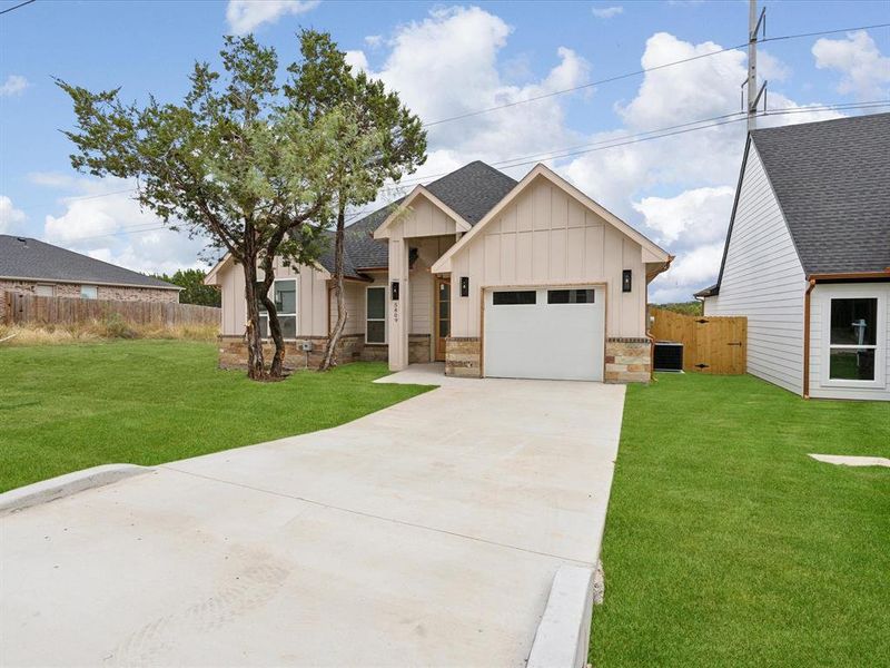 View of front facade featuring a garage, central air condition unit, and a front lawn