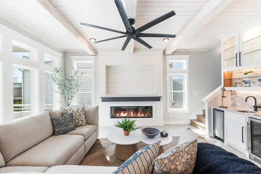 Living area with beverage cooler, a large fireplace, bar with sink, a ceiling fan, and a wood ceiling with exposed beams Living area with beverage cooler, a large fireplace, bar with sink, a ceiling fan, and a wood ceiling with exposed beams