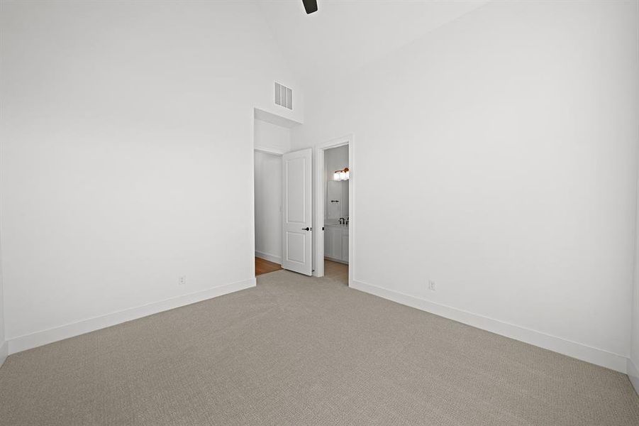 Unfurnished bedroom featuring high vaulted ceiling, carpet floors, ceiling fan, and ensuite bathroom Unfurnished bedroom featuring high vaulted ceiling, carpet floors, ceiling fan, and ensuite bathroom