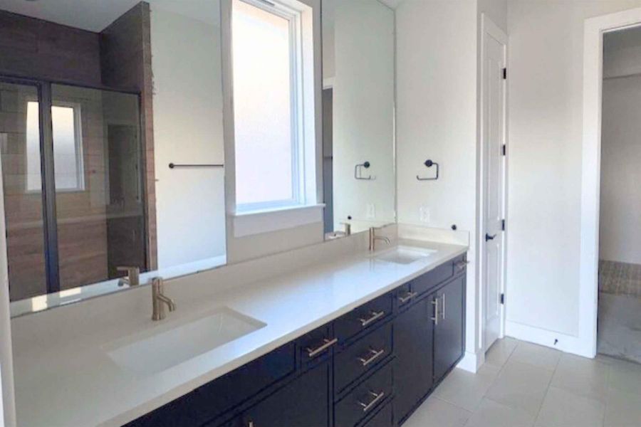 Full bathroom featuring a shower stall, double vanity, and light tile patterned floors