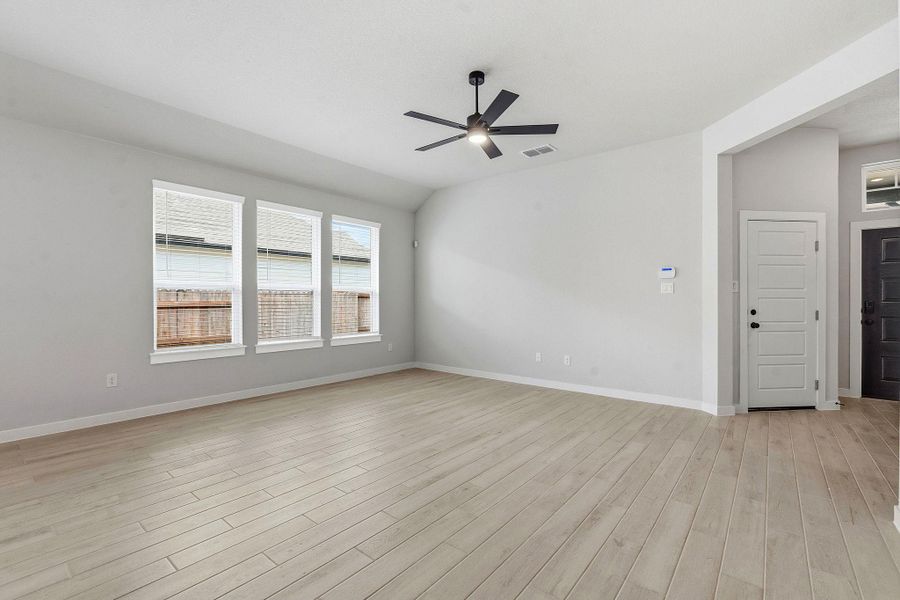 An airy living area boasts light wood-look flooring and multiple windows for abundant natural illumination.