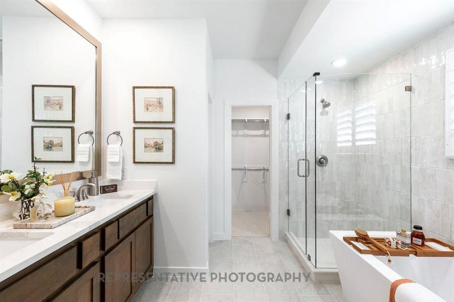 Bathroom featuring a stall shower, double vanity, light tile patterned floors, a freestanding bath, and a walk in closet