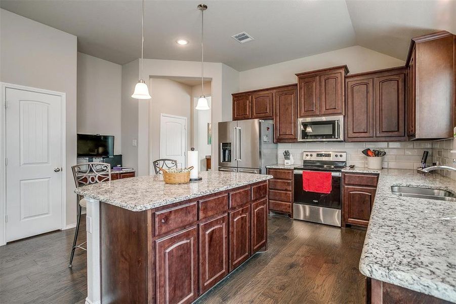 Kitchen featuring a center island, hanging light fixtures, sink, decorative backsplash, and appliances with stainless steel finishes