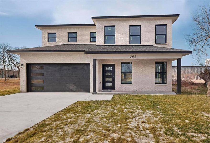 Contemporary house featuring covered porch, brick siding, a front yard, concrete driveway, and an attached garage Contemporary house featuring covered porch, brick siding, a front yard, concrete driveway, and an attached garage