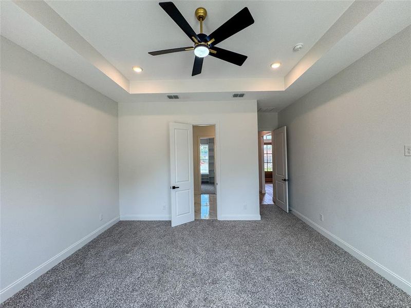Unfurnished bedroom with recessed lighting, a tray ceiling, carpet flooring, baseboards, and a ceiling fan Unfurnished bedroom with recessed lighting, a tray ceiling, carpet flooring, baseboards, and a ceiling fan