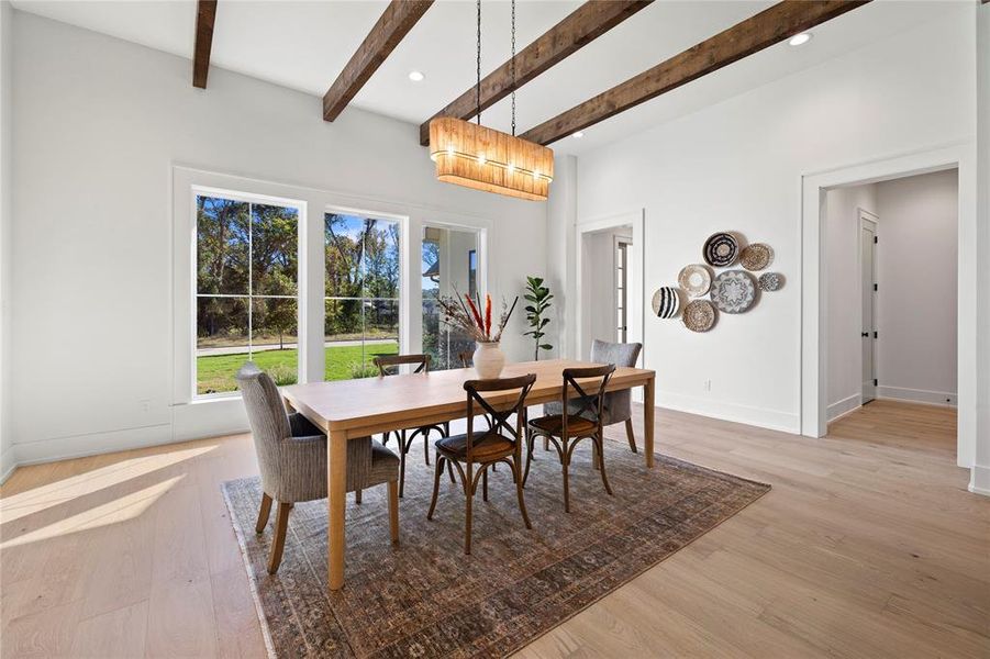 Dining area with light wood-style flooring, beamed ceiling, and recessed lighting