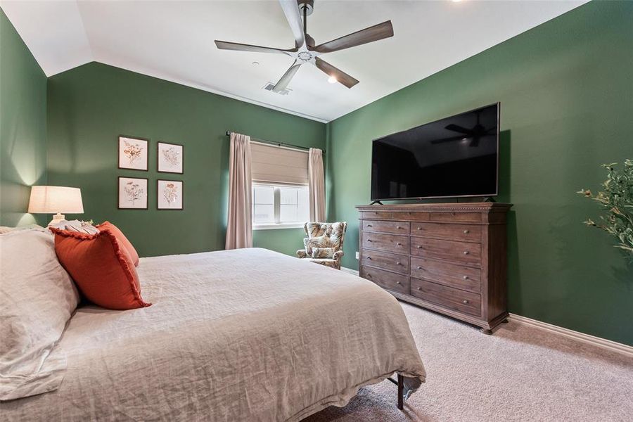 Bedroom featuring vaulted ceilings, a contemporary ceiling fan, plush carpet, a window with blinds and drapes, and a built-in wood-finish dresser Bedroom featuring vaulted ceilings, a contemporary ceiling fan, plush carpet, a window with blinds and drapes, and a built-in wood-finish dresser