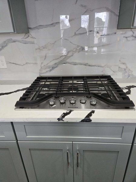 Interior details with backsplash, gray cabinets, and gas stovetop