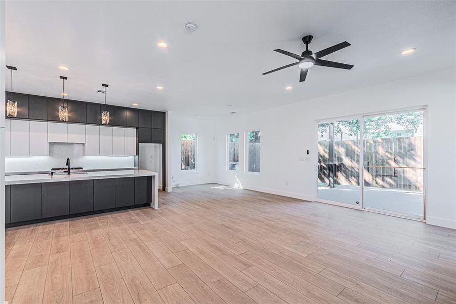 Kitchen with open floor plan, modern cabinets, dark cabinetry, recessed lighting, and hanging light fixtures