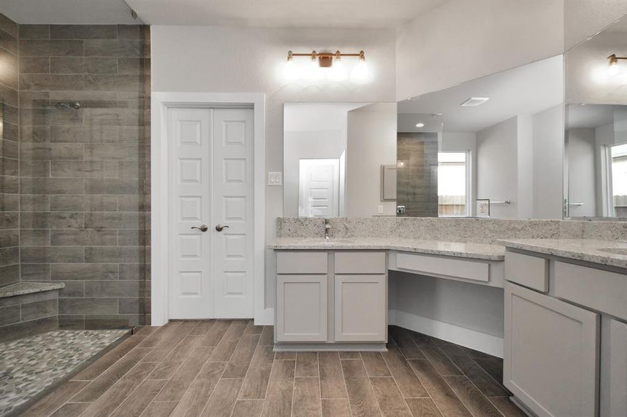 Full length mirrors, double sinks, modern vanity lights, and sleek hardware make this primary bathroom a sophisticated oasis of contemporary elegance and functionality. Sample photo of completed home with similar plan. As built color and selections will vary.