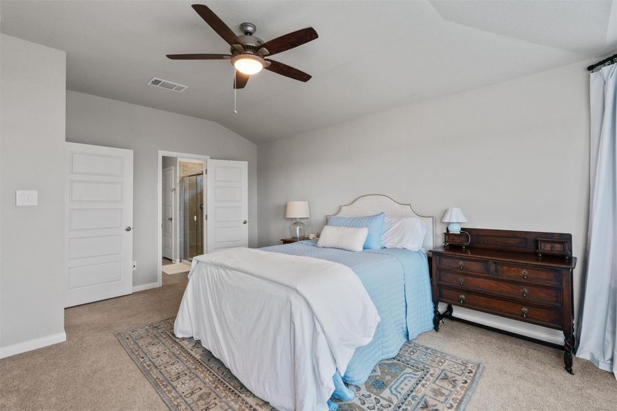 Carpeted bedroom featuring a vaulted ceiling, ceiling fan, and light gray wall paint Carpeted bedroom featuring a vaulted ceiling, ceiling fan, and light gray wall paint