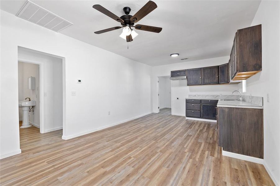 Kitchen with light countertops, dark brown cabinetry, light wood finished floors, and a ceiling fan Kitchen with light countertops, dark brown cabinetry, light wood finished floors, and a ceiling fan