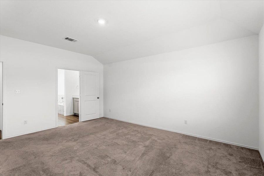 Unfurnished bedroom with vaulted ceiling, carpet floors, and ensuite bath