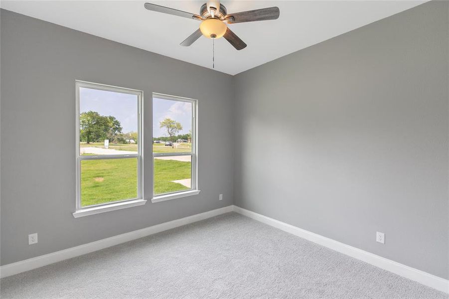 Carpeted spare room featuring ceiling fan and a healthy amount of sunlight