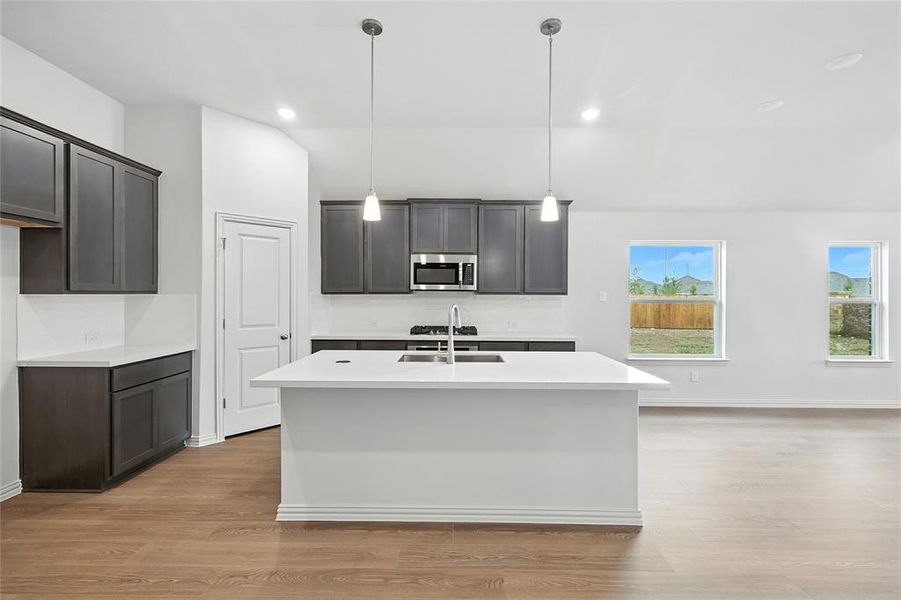 Kitchen featuring light wood-style floors, decorative light fixtures, light stone counters, a kitchen island with sink, and recessed lighting Kitchen featuring light wood-style floors, decorative light fixtures, light stone counters, a kitchen island with sink, and recessed lighting