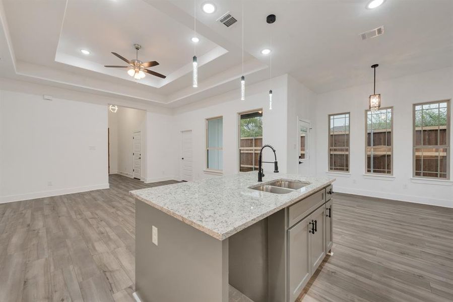 Kitchen featuring a wealth of natural light, sink, a kitchen island with sink, and decorative light fixtures