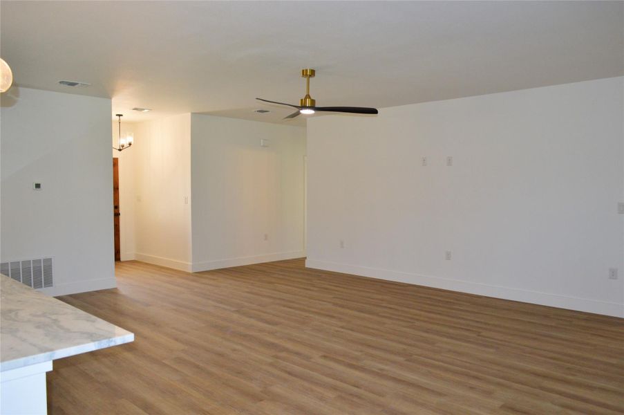 Unfurnished living room with light wood finished floors, a chandelier, and ceiling fan Unfurnished living room with light wood finished floors, a chandelier, and ceiling fan