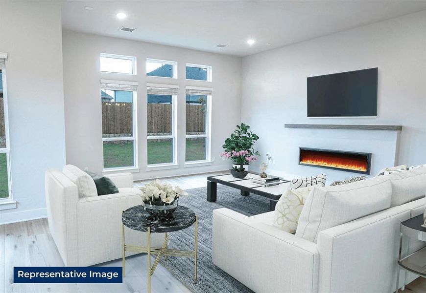 Living room featuring a warm lit fireplace, light wood-type flooring, and recessed lighting