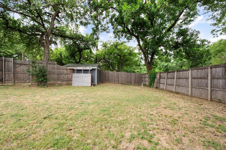 Fenced backyard with a storage unit and view of wooded area Fenced backyard with a storage unit and view of wooded area
