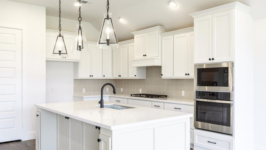 Kitchen featuring a sink, built in microwave, backsplash, white cabinets, and recessed lighting
