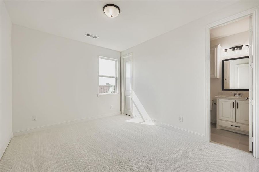 Unfurnished bedroom featuring light colored carpet and ensuite bathroom