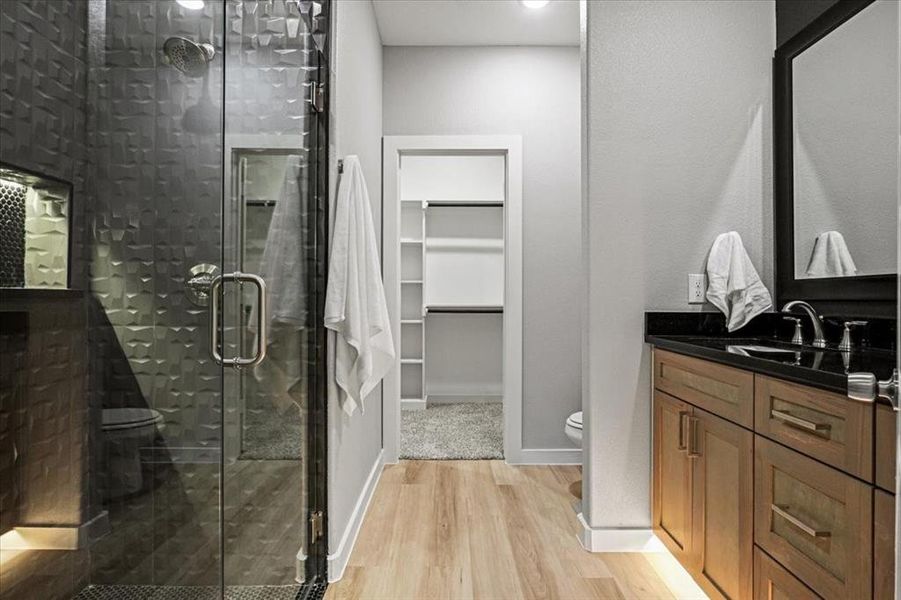 Bathroom featuring a shower with door, vanity, wood-type flooring, and toilet