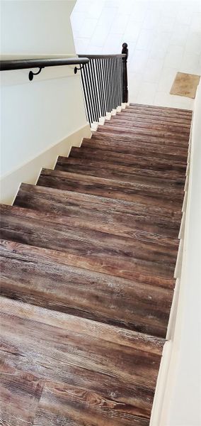 Vinyl flooring on staircase along with black rought iron railing.