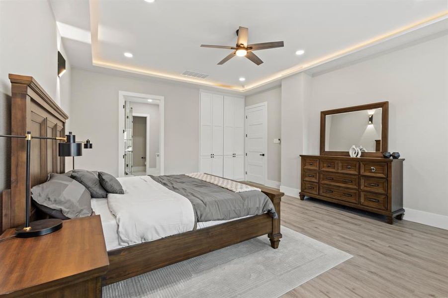 Bedroom with recessed lighting, light wood finished floors, a ceiling fan, and a raised ceiling