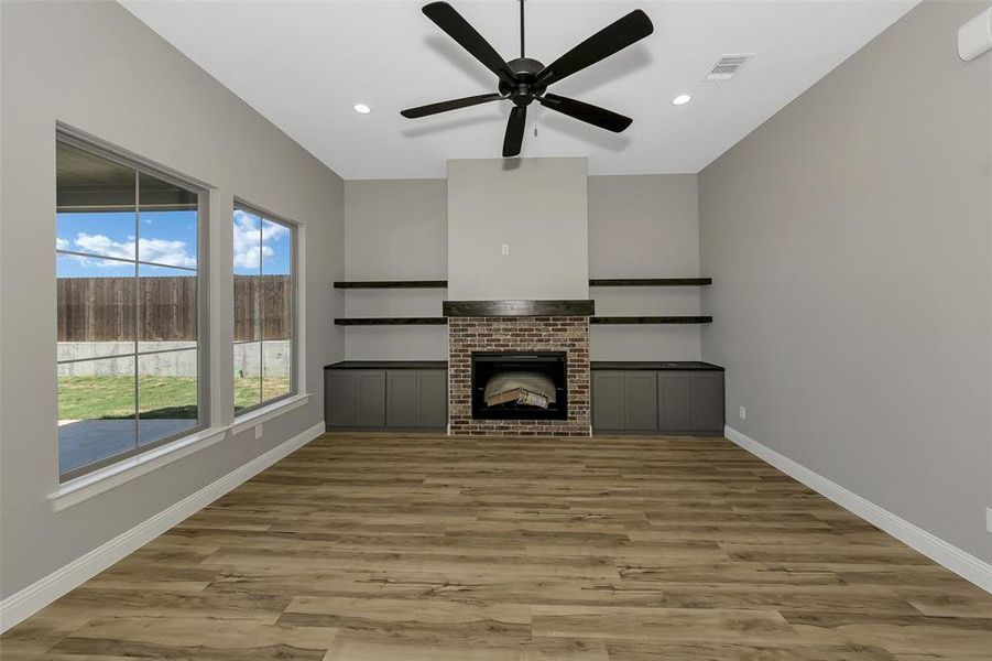 Unfurnished living room featuring wood finished floors, a ceiling fan, recessed lighting, and a brick fireplace