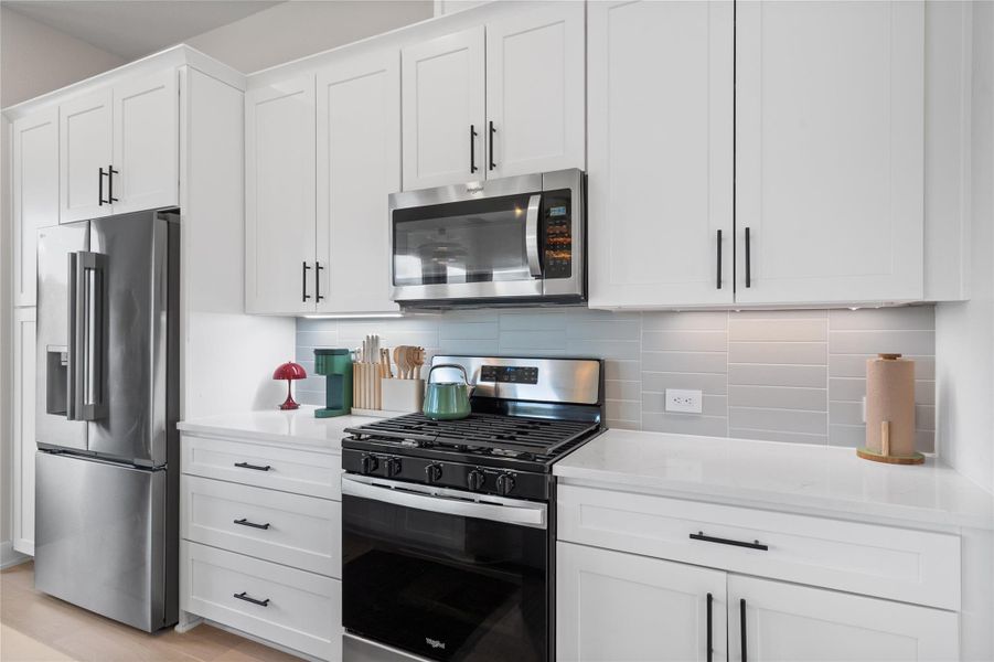 White cabinetry, stainless steel appliances, and a tiled backsplash adorn this well-appointed kitchen. White cabinetry, stainless steel appliances, and a tiled backsplash adorn this well-appointed kitchen.