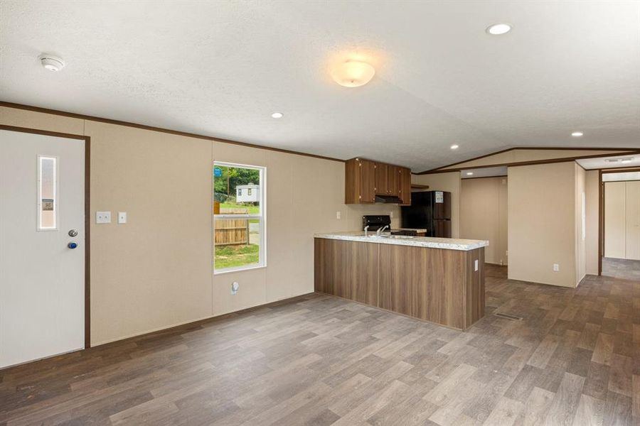 Open-concept living area featuring wood-finish flooring, recessed lighting, and a kitchen island with a stone-look countertop