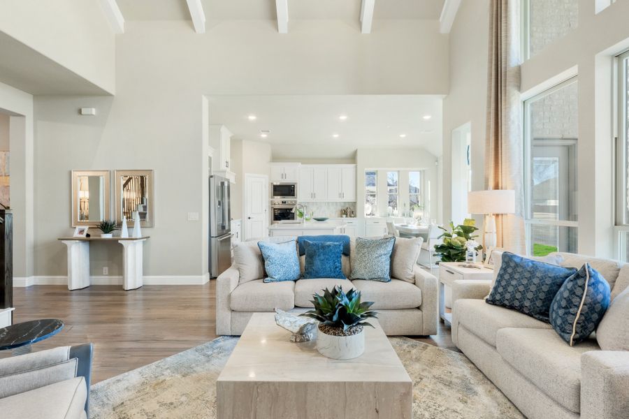 Open-concept living room with high beamed ceiling, hardwood floors, and view into white kitchen Open-concept living room with high beamed ceiling, hardwood floors, and view into white kitchen