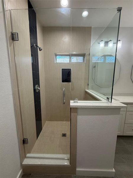 Bathroom with a stall shower, vanity, and recessed lighting