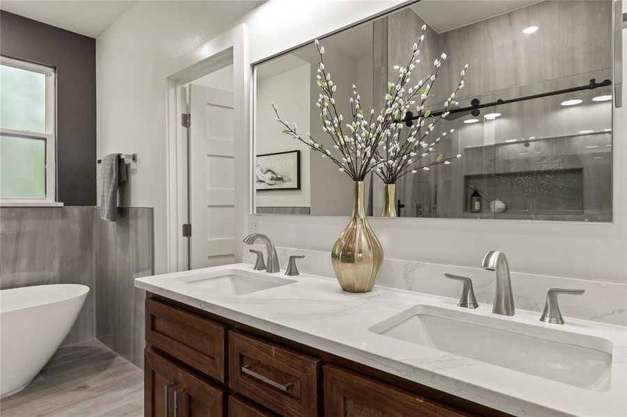 Full bathroom with double vanity, a soaking tub, wood finished floors, wainscoting, and tile walls