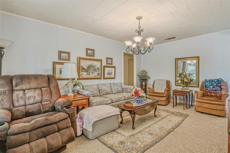 Inviting living space featuring light blue walls, textured ceiling, a decorative chandelier, and plush carpeting Inviting living space featuring light blue walls, textured ceiling, a decorative chandelier, and plush carpeting