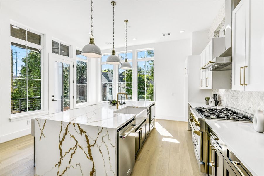 Flooded with natural light, this show stopping kitchen showcases floor-to-ceiling windows, a massive waterfall-edge quartz island with dramatic gold veining, and custom two-tone cabinetry accented by brushed brass hardware. Pendant lighting and professional-grade appliances elevate both style and performance—perfect for the discerning professional who values luxury andpracticality.