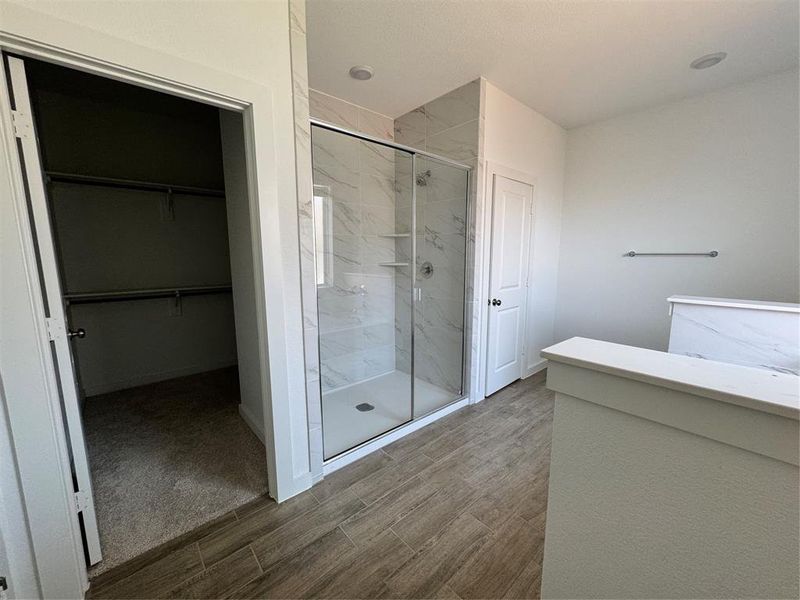 Bathroom with a marble finish shower, wood finished floors, and a spacious closet Bathroom with a marble finish shower, wood finished floors, and a spacious closet