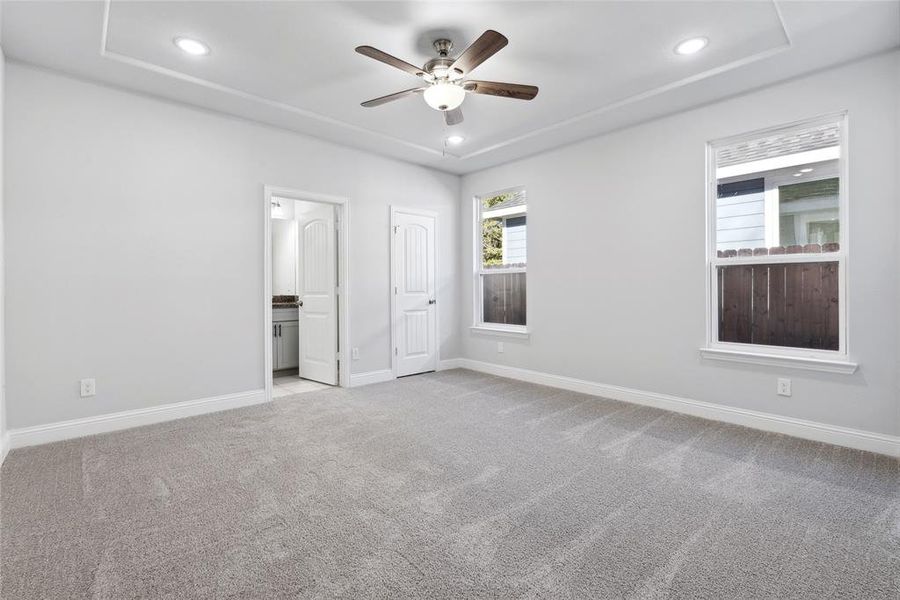 Unfurnished bedroom featuring ceiling fan, light carpet, and ensuite bath