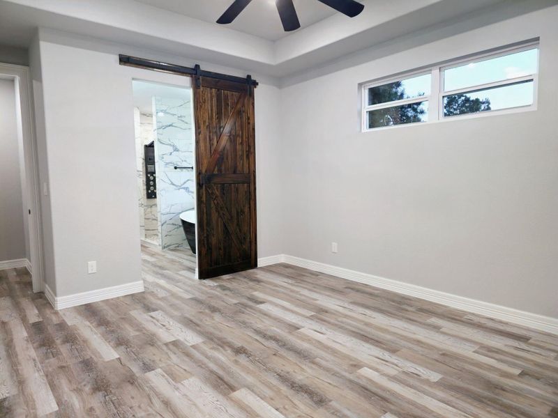 Primary bedroom features a rustic sliding barn door leading to a modern bathroom.