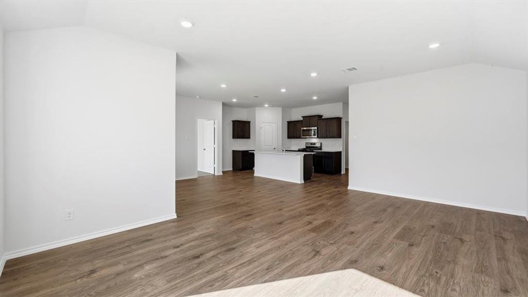 Unfurnished living room with dark wood-style flooring, recessed lighting, and vaulted ceiling Unfurnished living room with dark wood-style flooring, recessed lighting, and vaulted ceiling