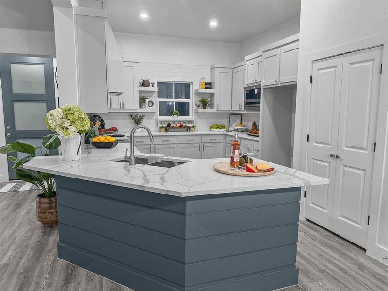 Kitchen with sink, stainless steel microwave, light quartz counters, and kitchen peninsula