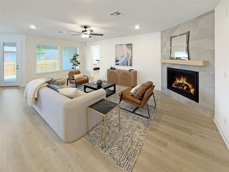 Living area featuring light wood finished floors, a tiled fireplace, ceiling fan, and recessed lighting