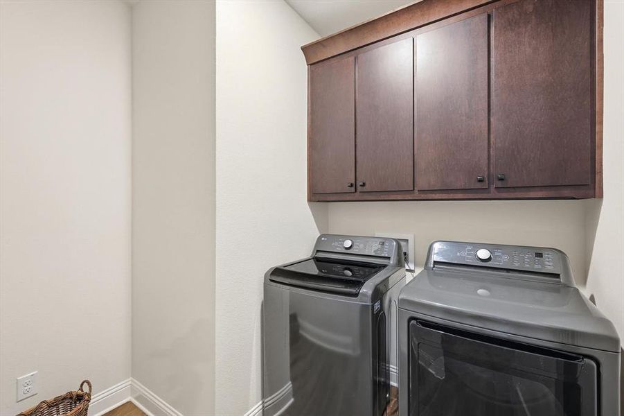 Laundry area with cabinet space, separate washer and dryer, and wood finished floors
