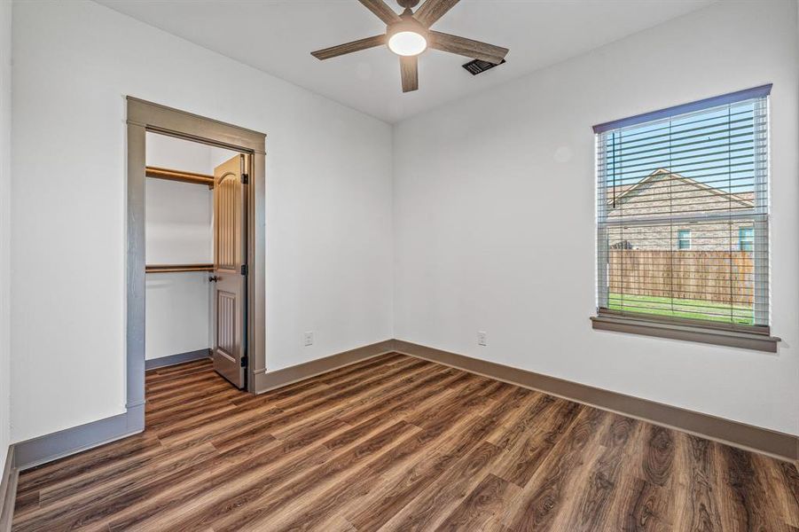 Unfurnished bedroom with dark wood finished floors, ceiling fan, and a walk in closet