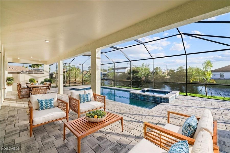 View of patio / terrace featuring a water view, a sunroom, a lanai, a pool with connected hot tub, and an outdoor hangout area