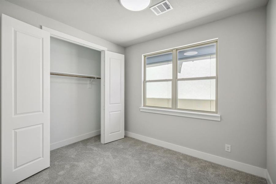 Unfurnished bedroom with light carpet and a closet