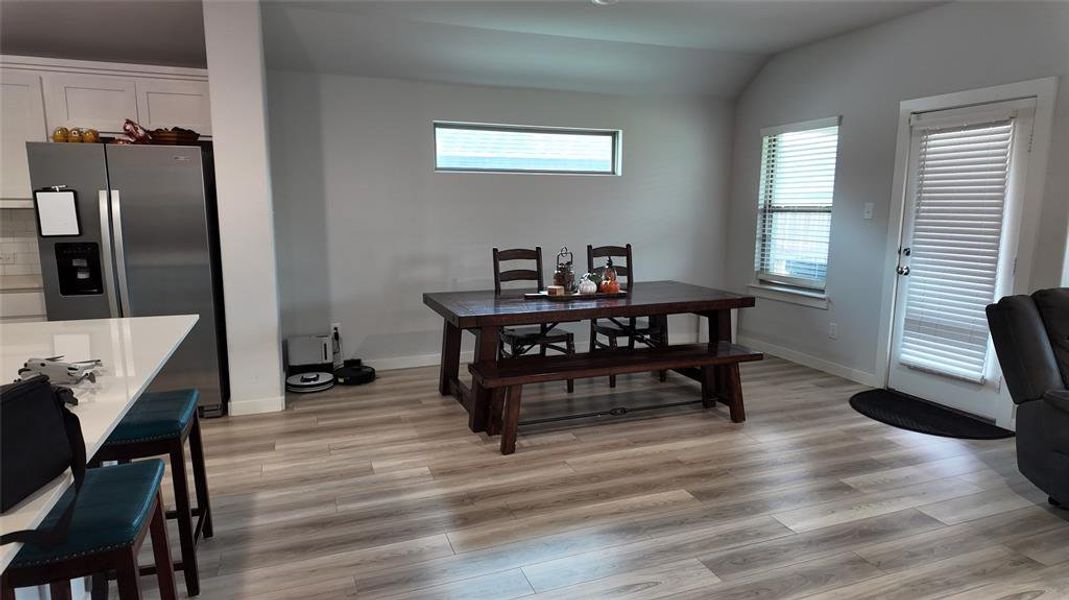 Open concept living area featuring light-colored flooring, a dining area with a dark wood table, and a kitchen island with seating