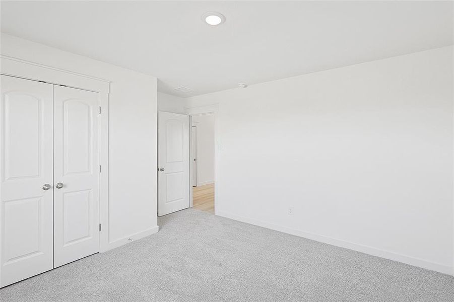 Unfurnished bedroom with light colored carpet and a closet