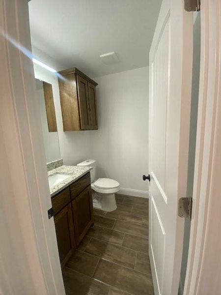Bathroom featuring vanity, toilet, and baseboards